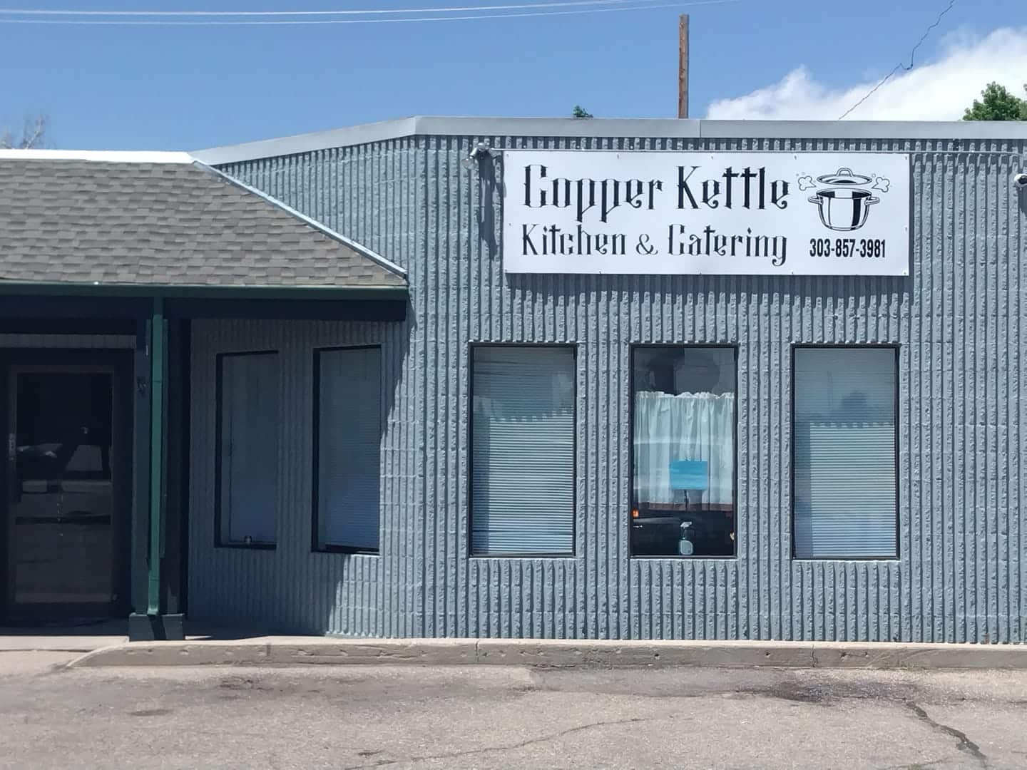 Outside of blue brick building with "Copper Kettle Kitchen and Cathering" sign