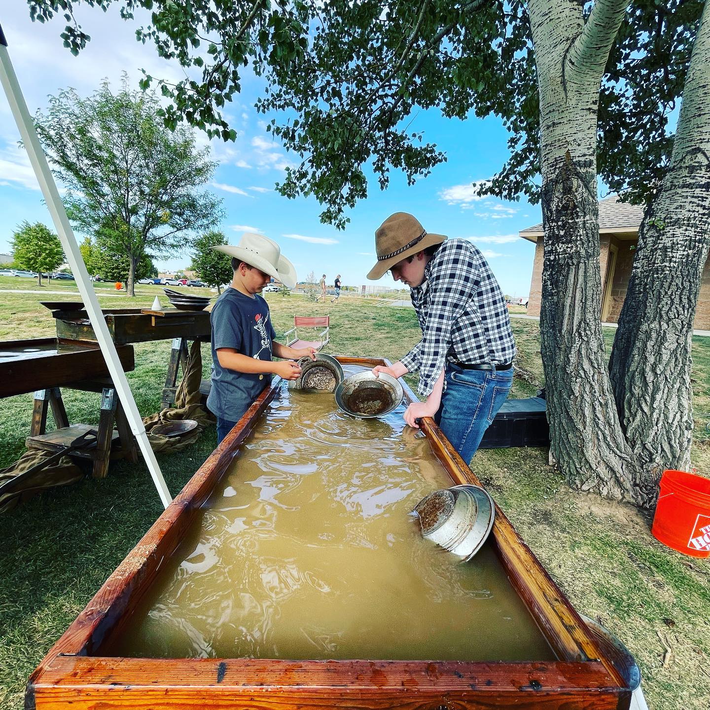 Two visitors panning for materials in a water trough