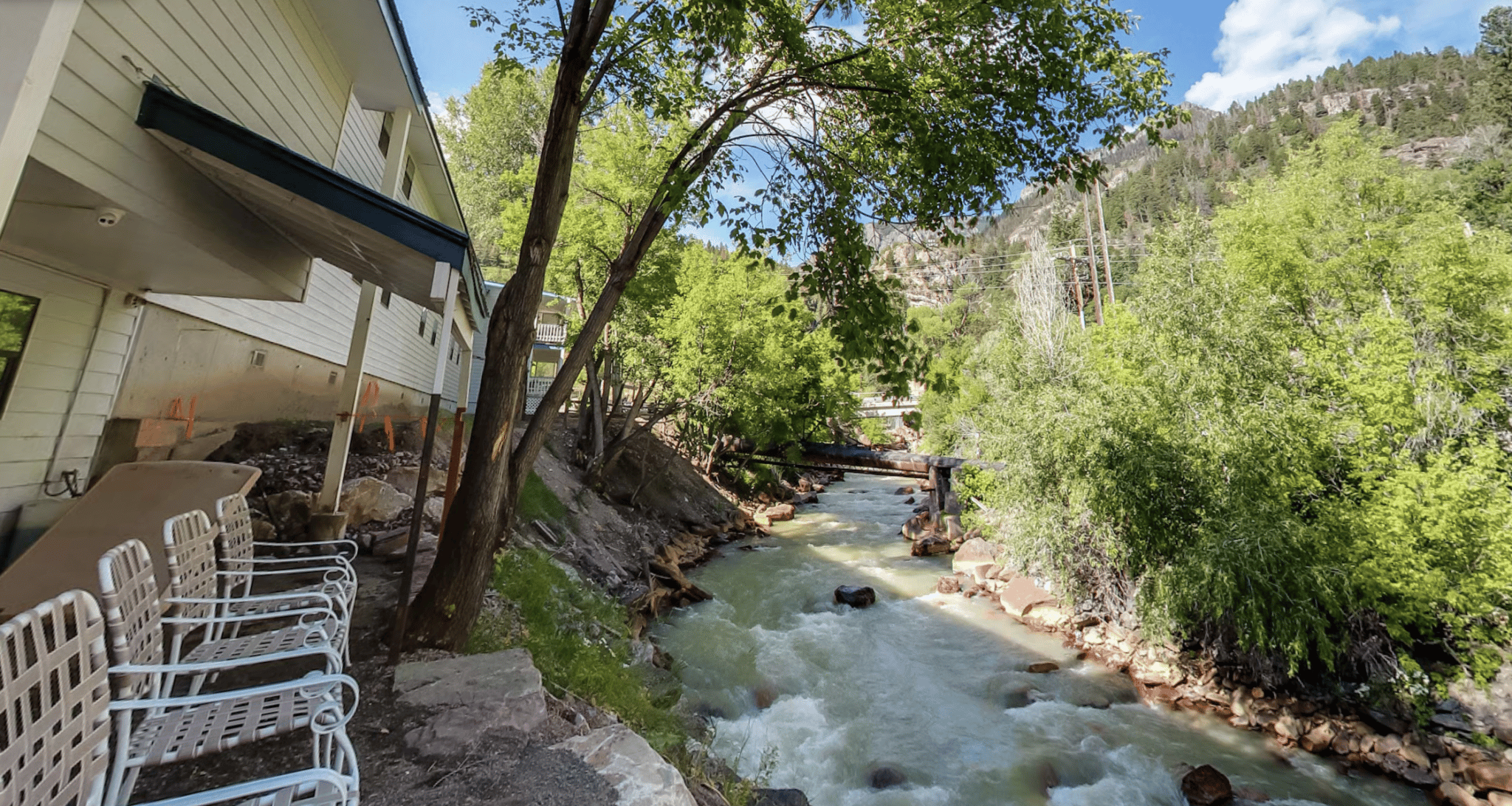 River running behind a hotel property with 4 chairs