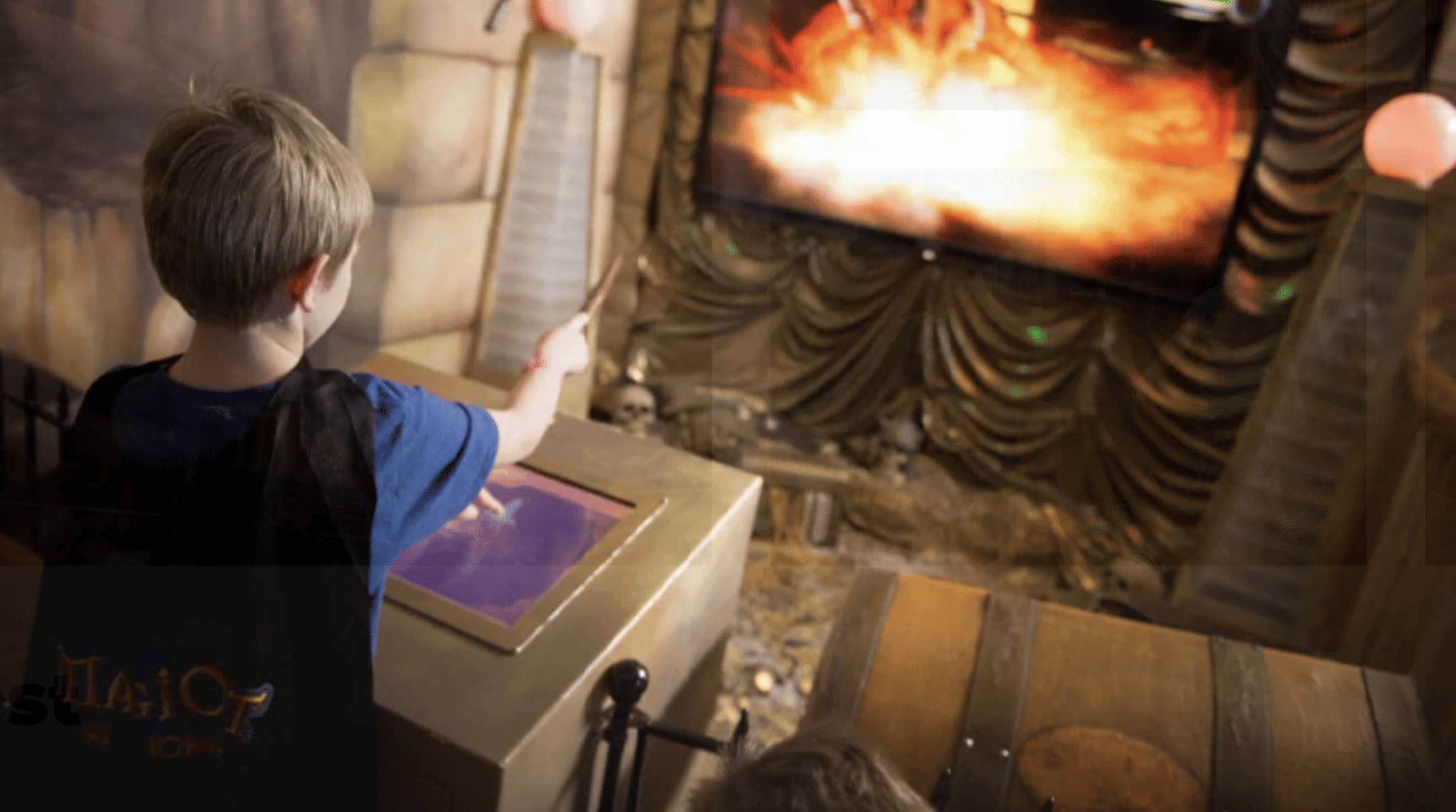 Kid pointing a wand at a screen with a fireplace on it