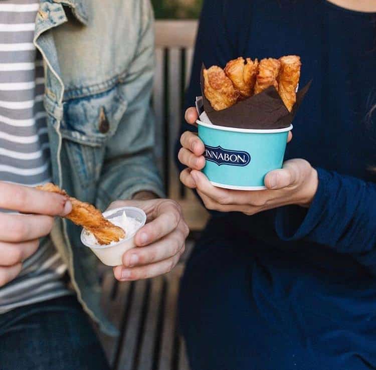 Two people holding cinnabon bites