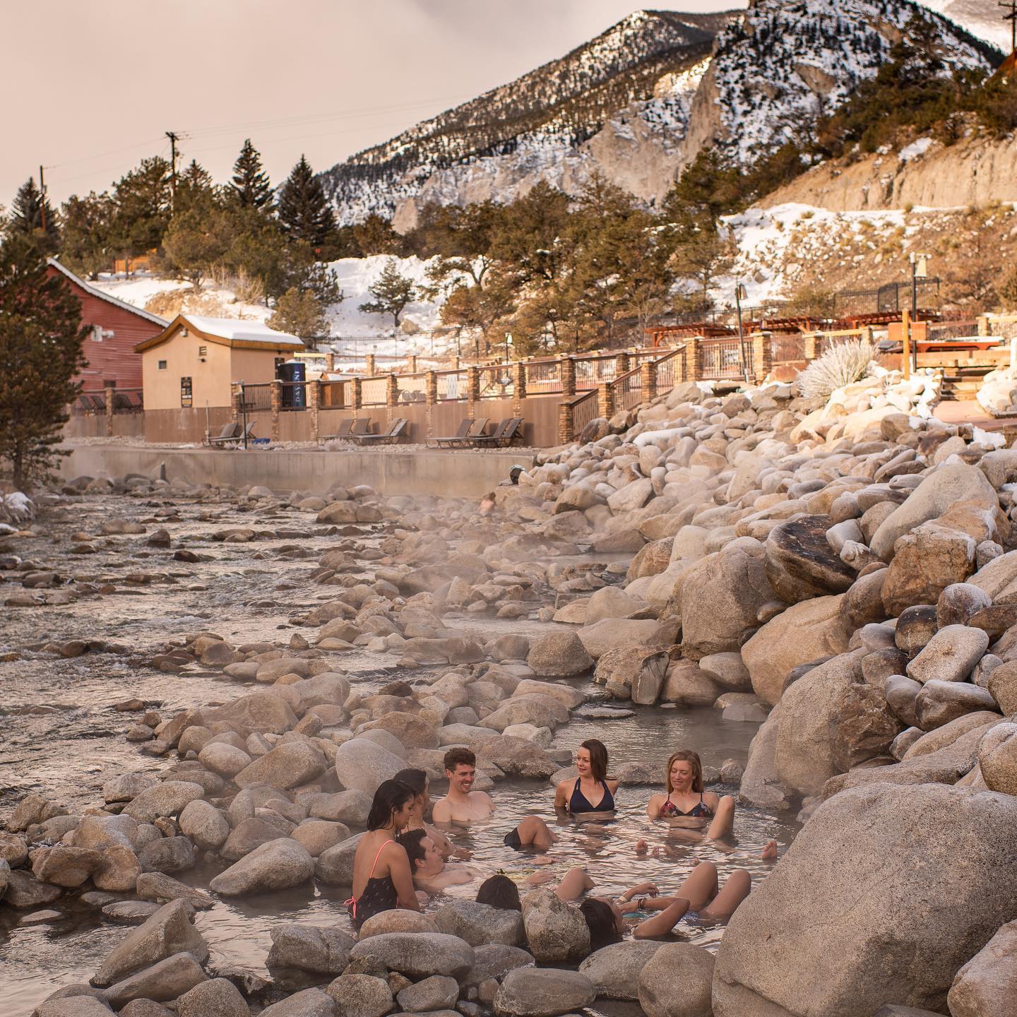 Group of people relaxing in a creekside primitive hot springs pool. 