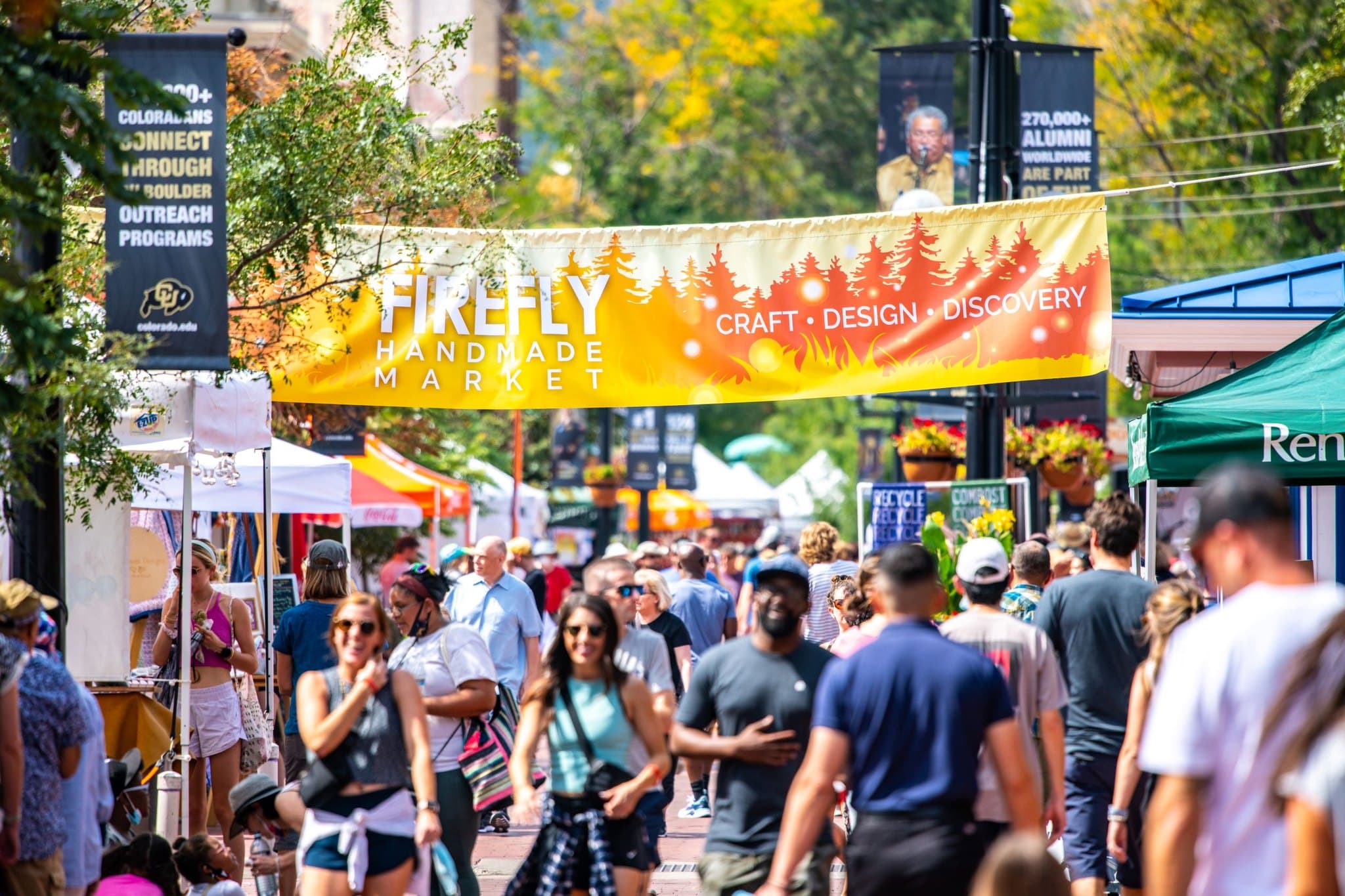 Large yellow banner for Firefly Handmade Market hanging over a crowd of people walking on a street