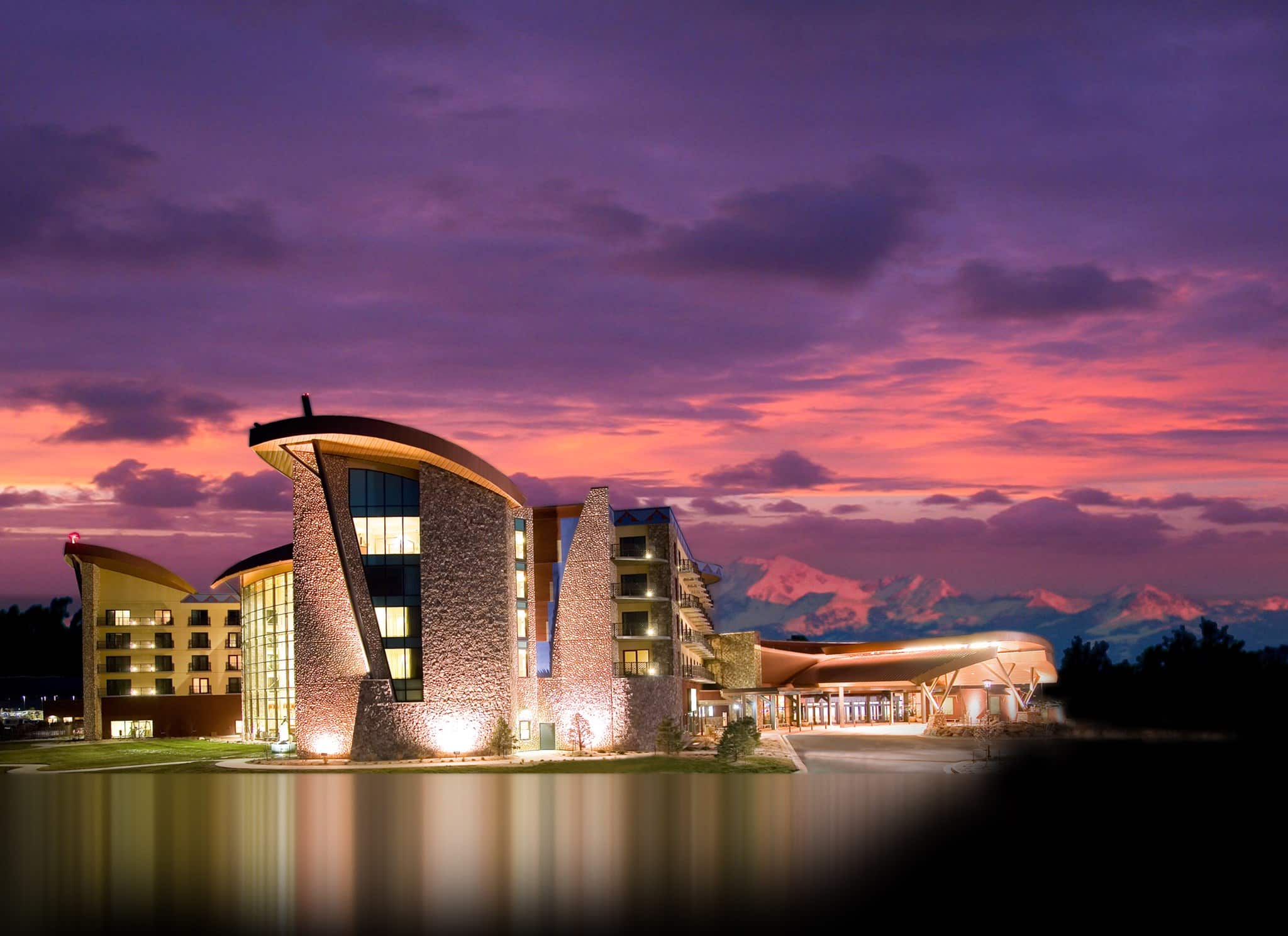 purple and pink sunset and uplit large casino hotel in front of a small lake