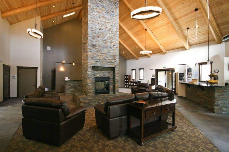 Lobby reception with a large grey stone fireplace and black leather seating