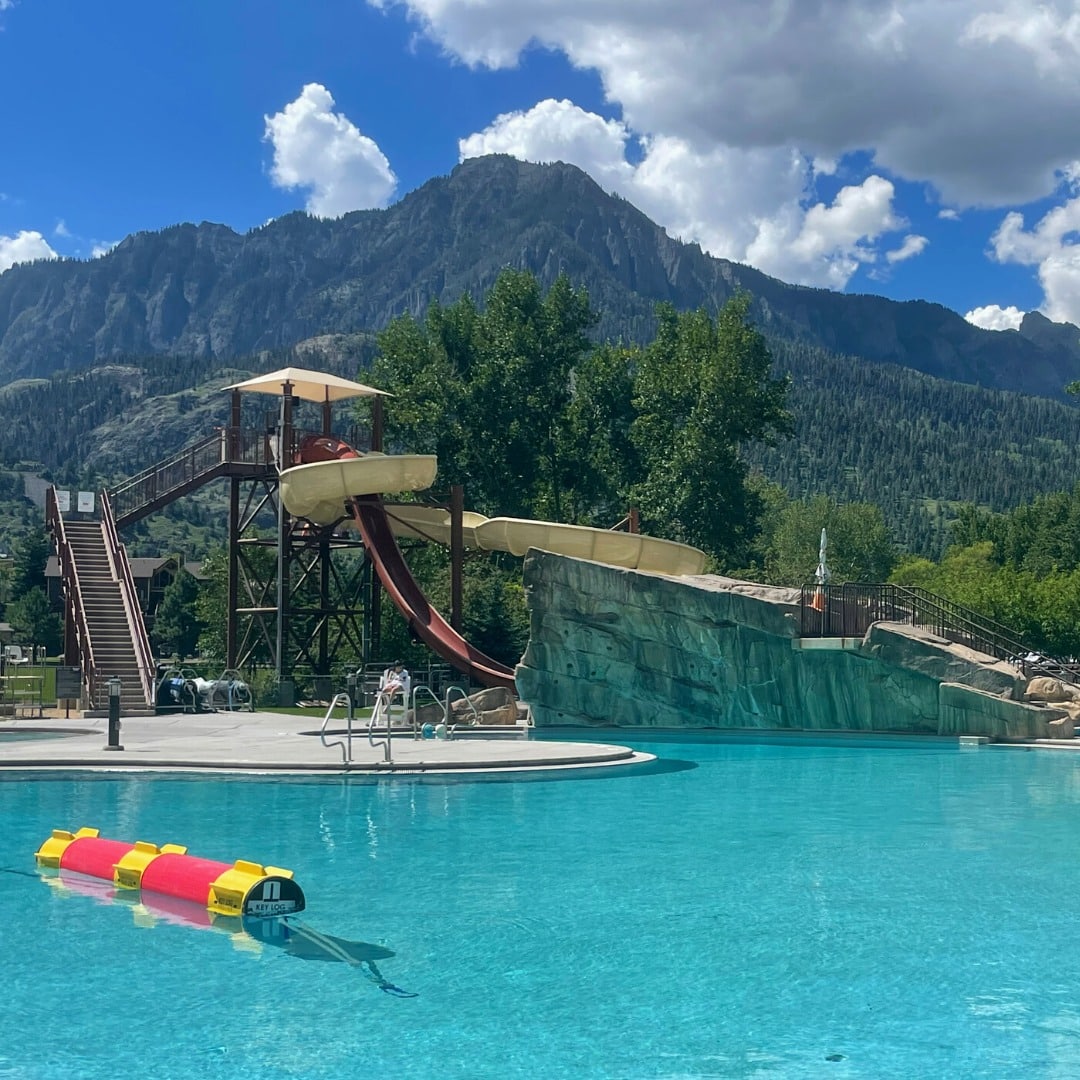 Two outdoor water slides in front of mountains