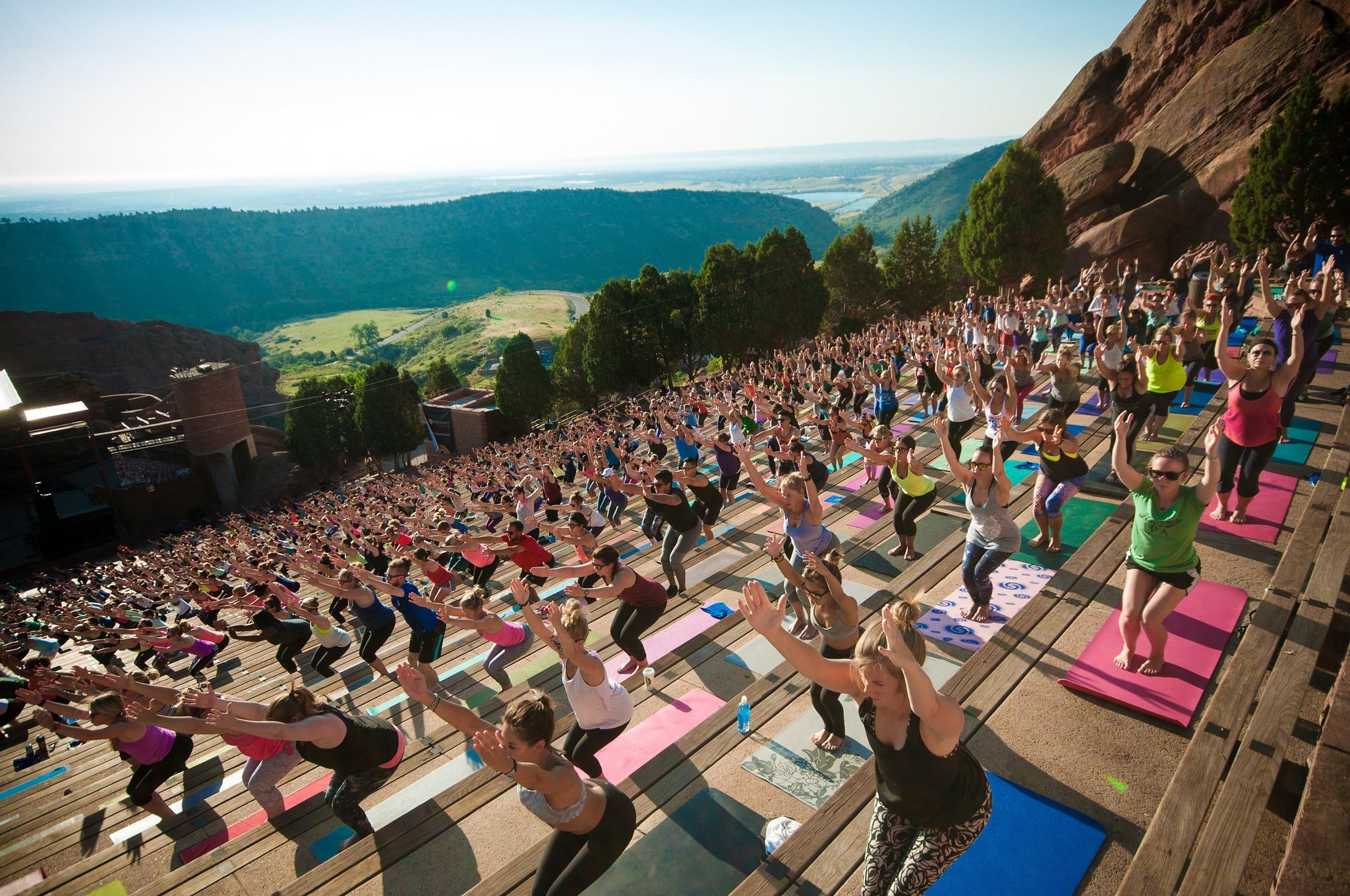 Hundreds of people on yoga mats lined up on the steps of Red Rocks Amphitheare in Morrison. 