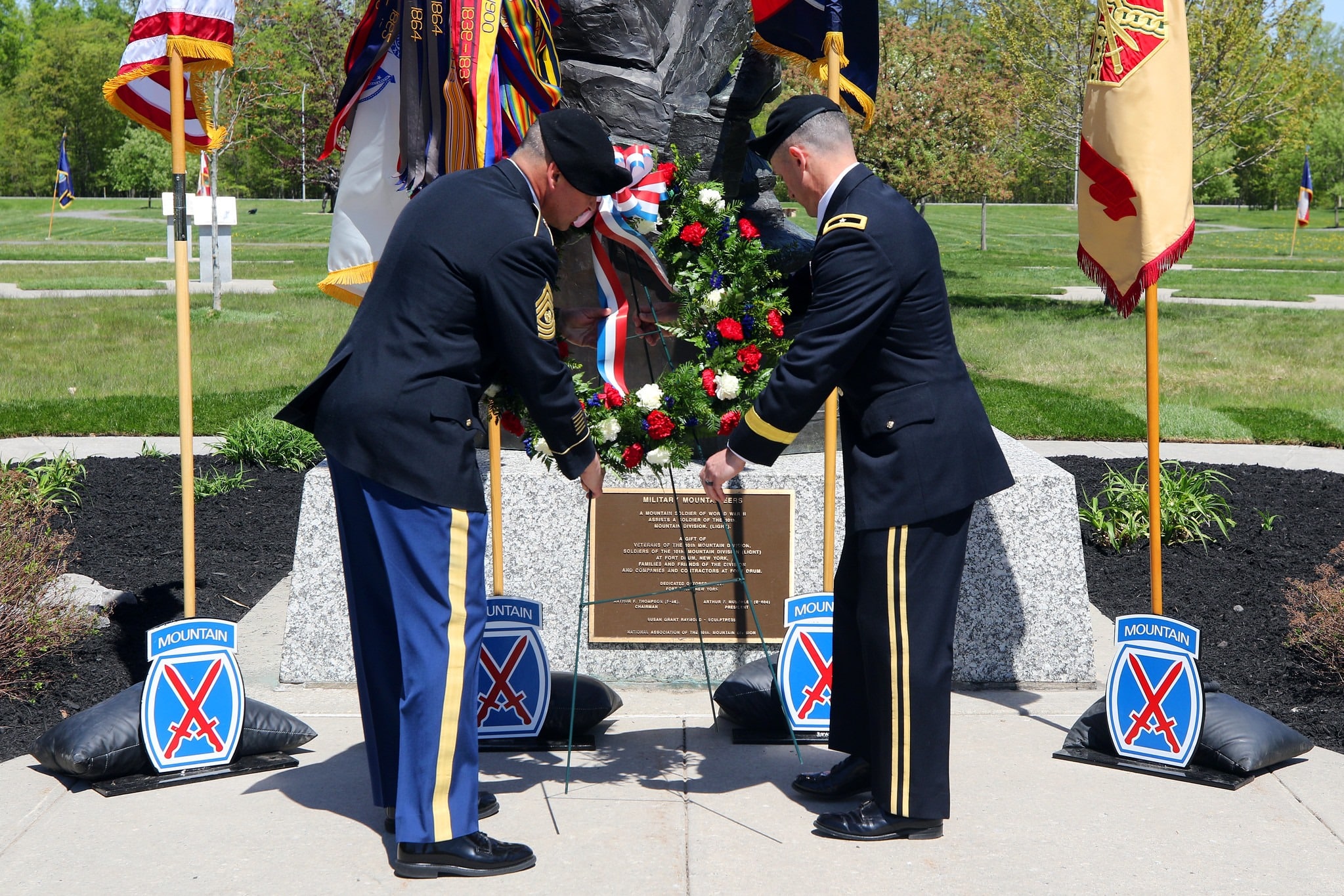 Two dressed service men laying a wreath on a memorial