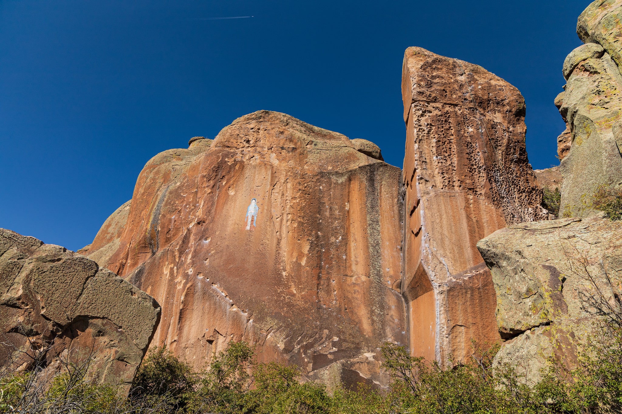 Large red rock walls with a small man-shaped rock painting