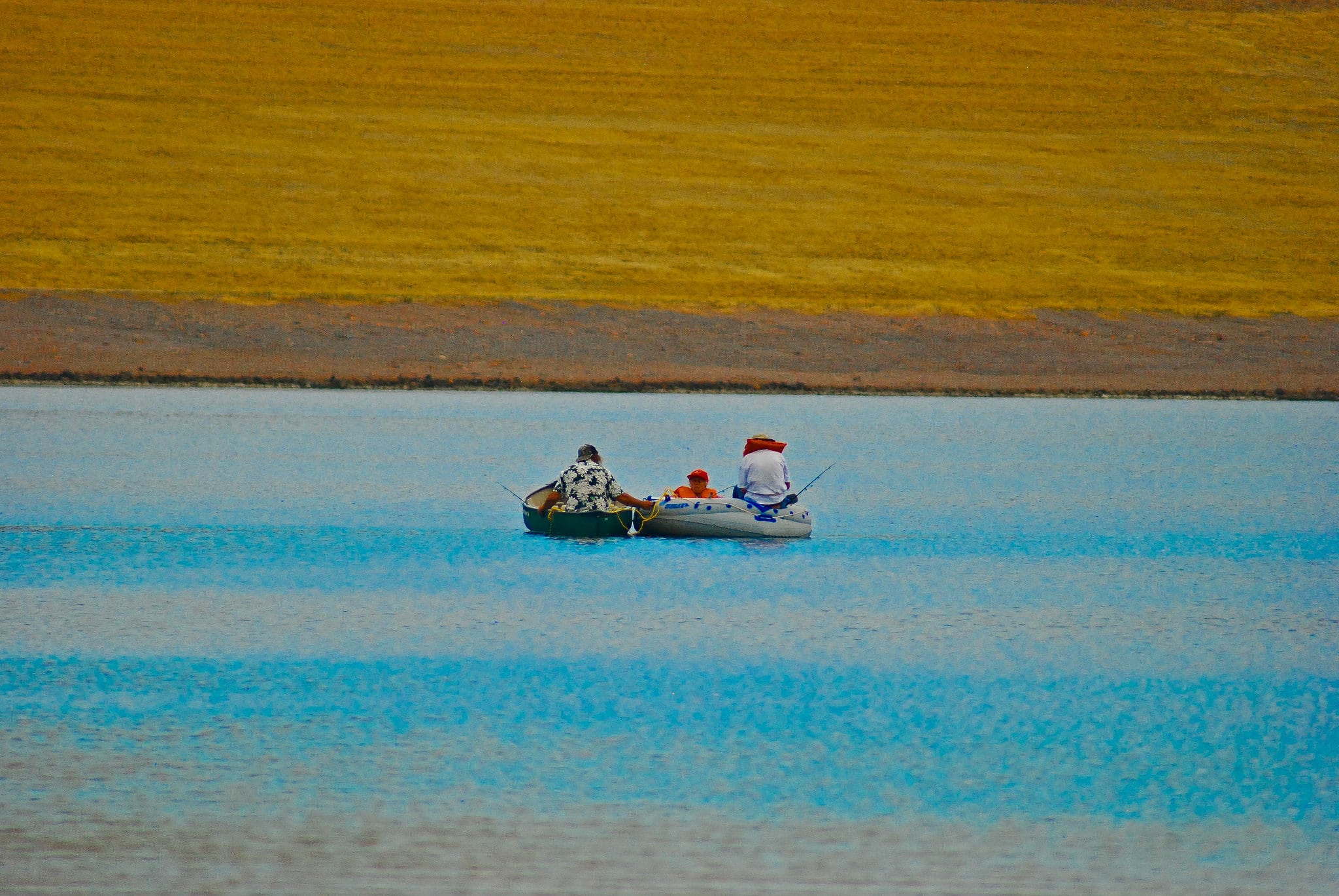 Zoomed in shot of small boat on a lake with three fishermen