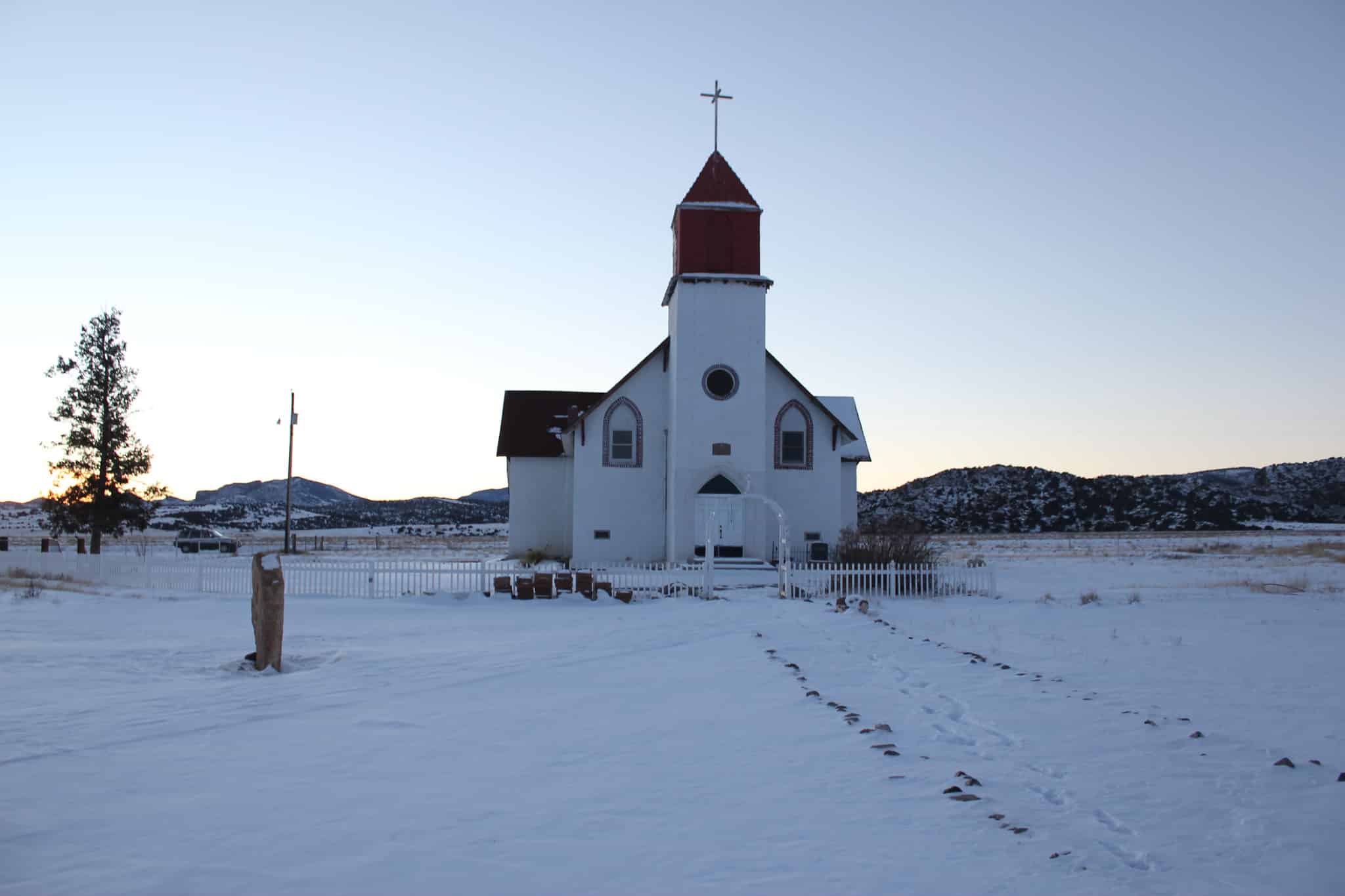 Snow on the ground surrounding a white church 