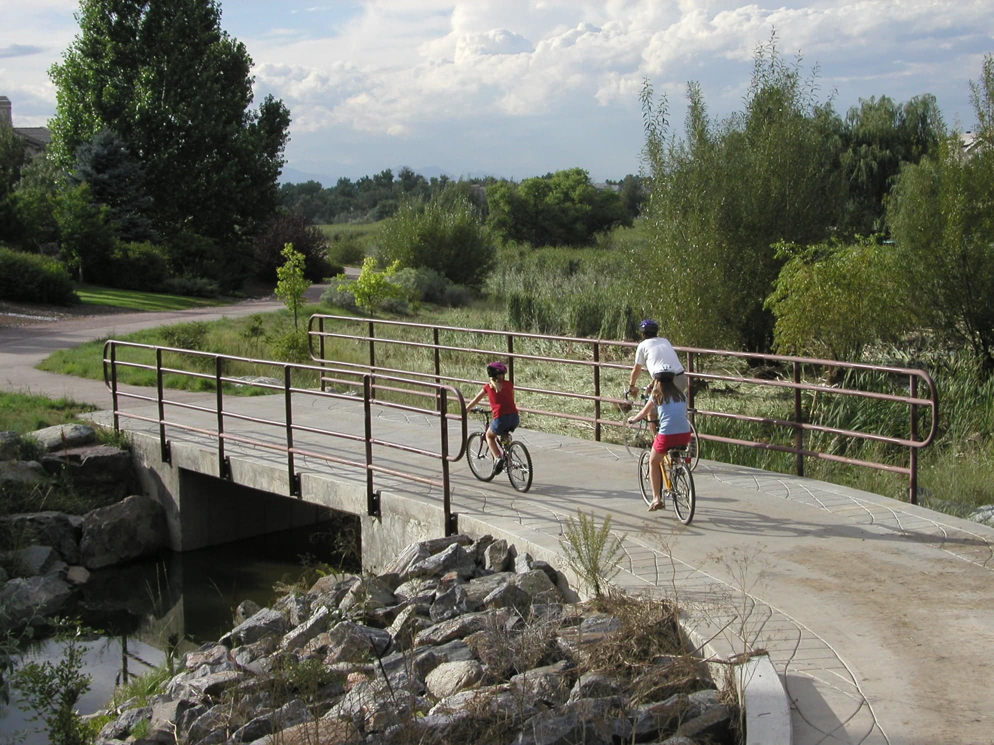 Paved biking path with 3 people riding bikes on it