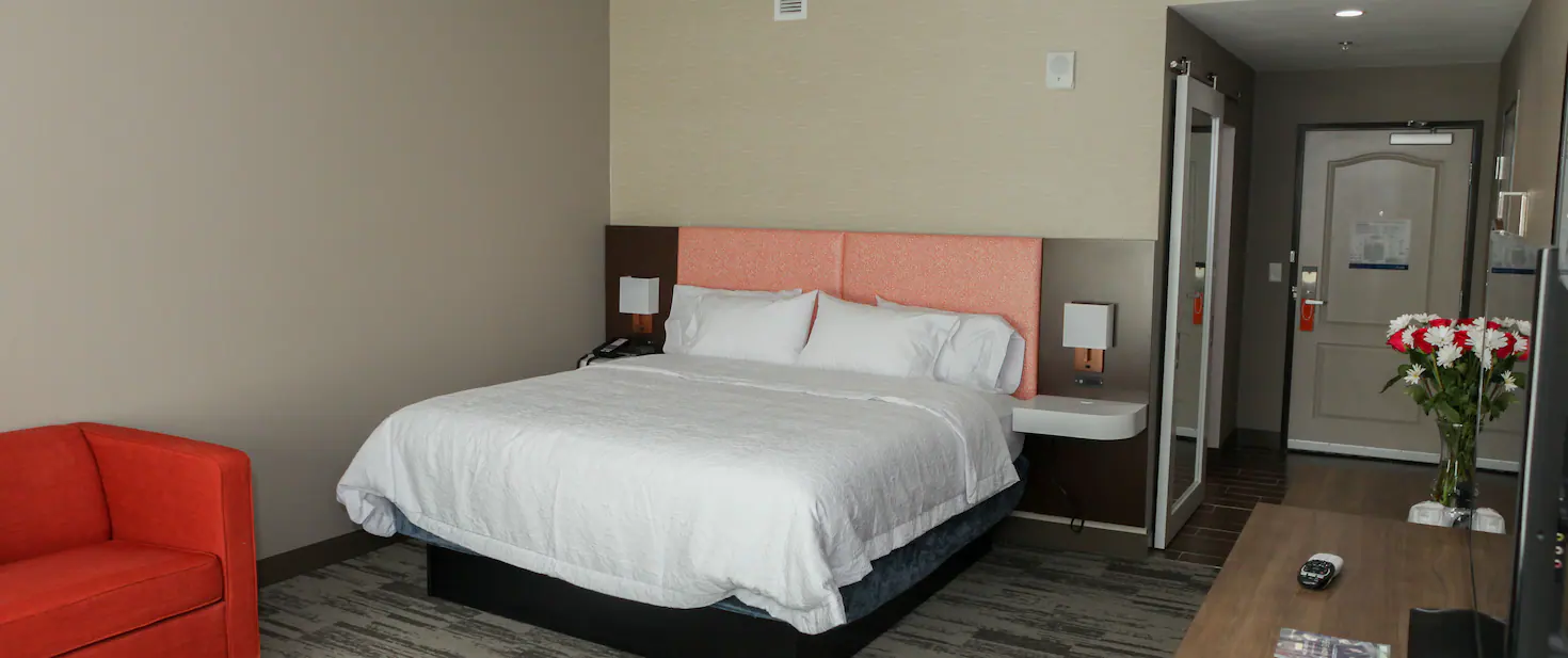 Guest room at a hotel with a white bed and red couch