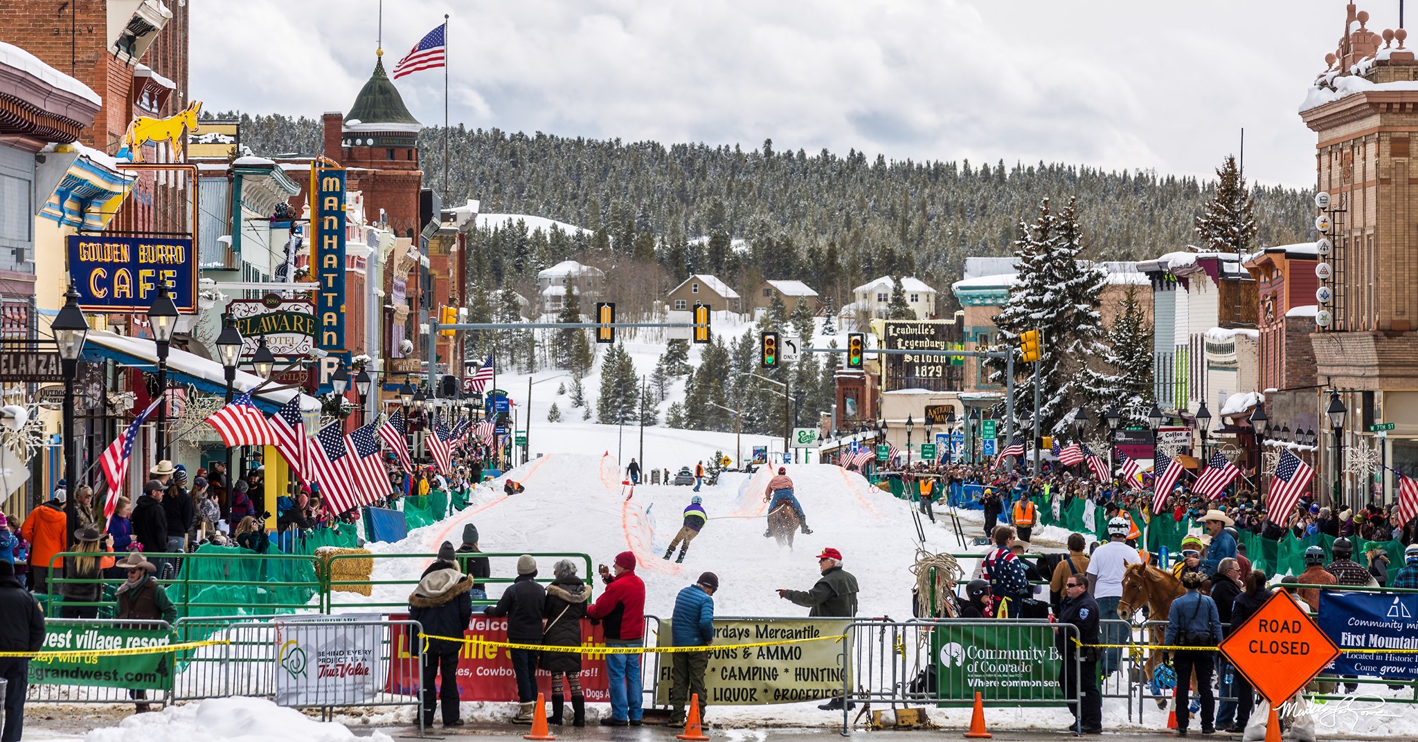 Main street of a small town filled with people watching a snow racing event