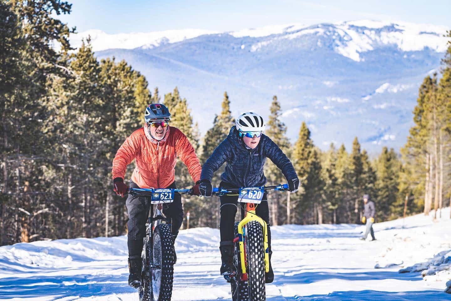 Two people on mountain bikes on a snowy forest trail