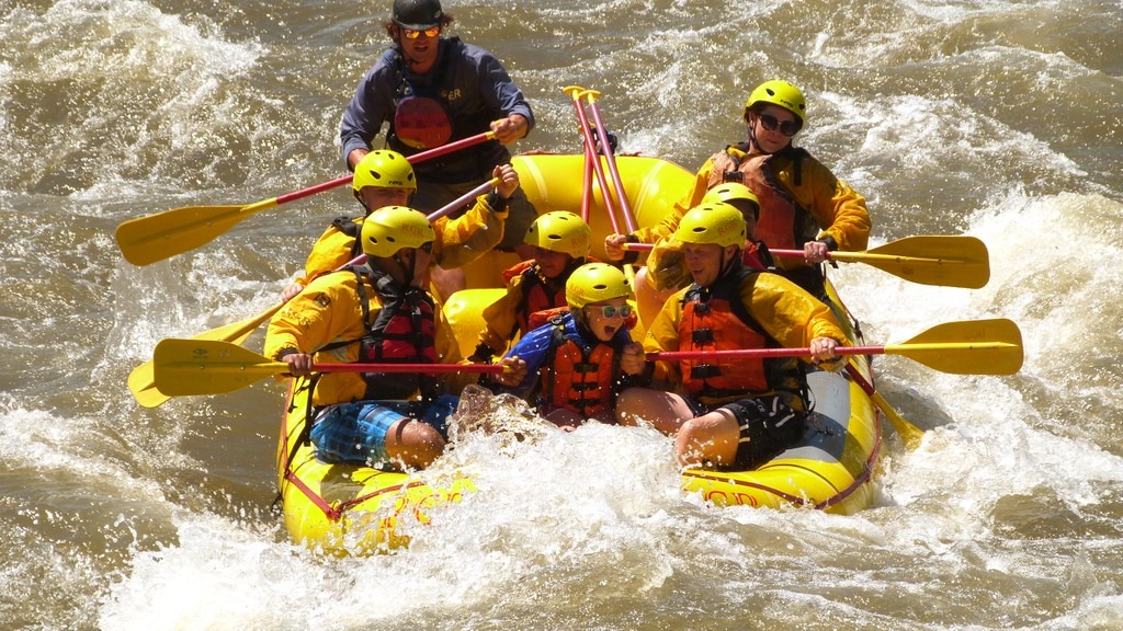 Group of rafters in yellow helmets and orange vests on a whitewater raft in the Royal Gorge