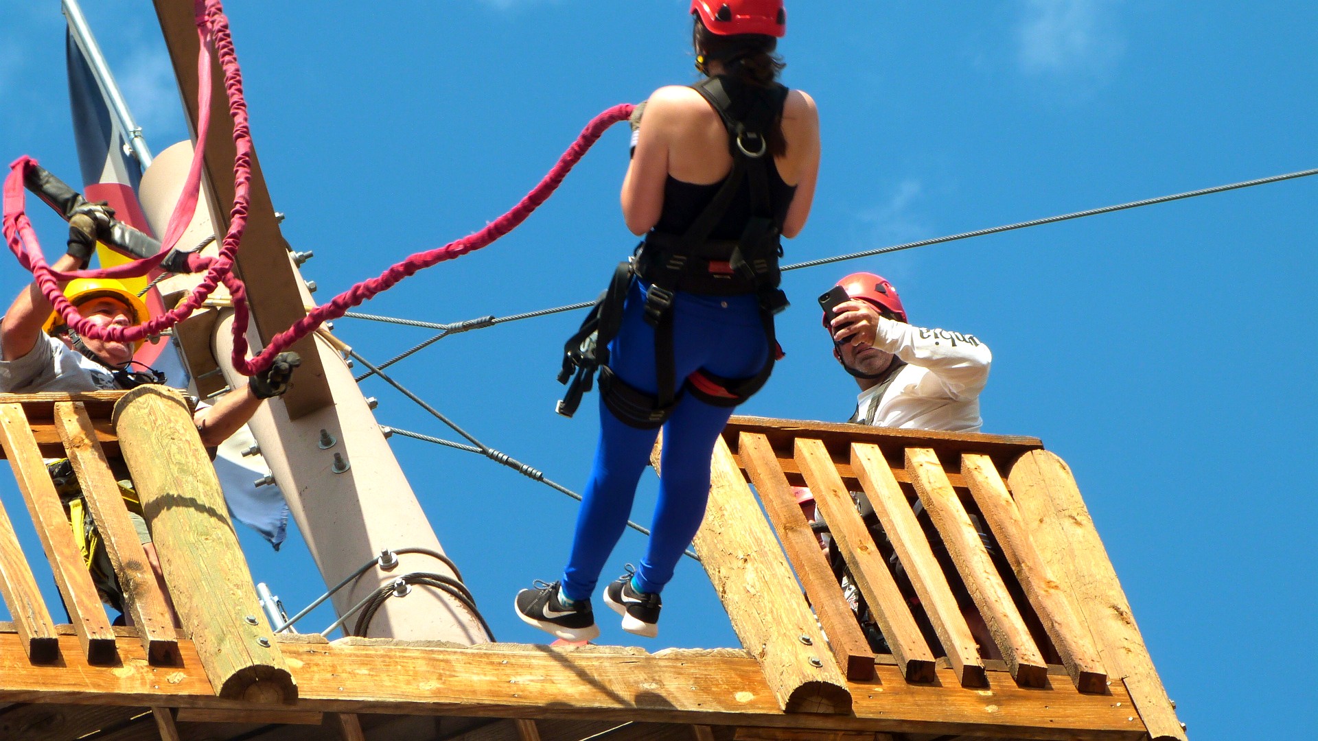 Person hooked up to a thick red tether, leaning back to freefall off a platform at Royal Gorge Zipline Tours