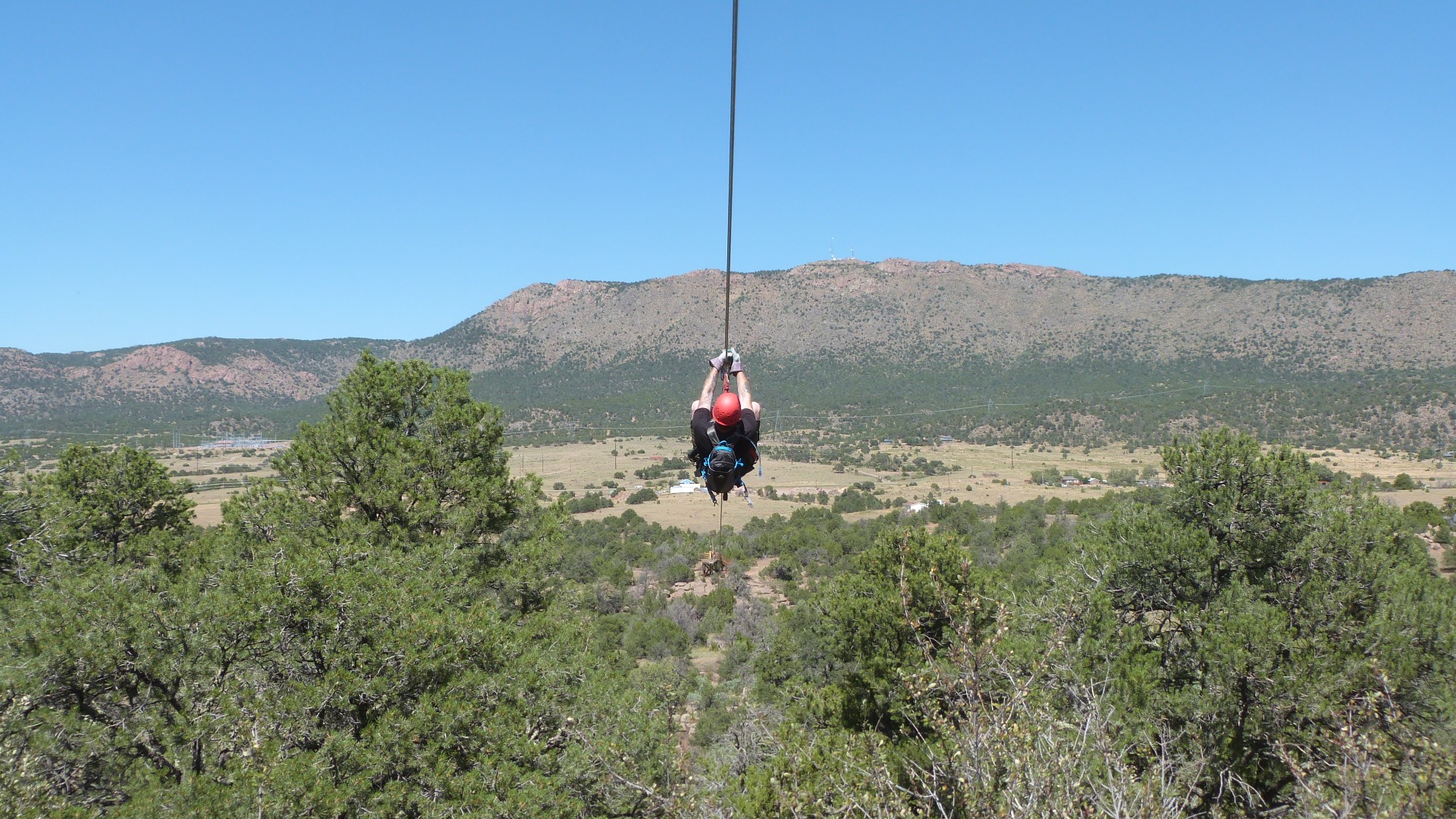 Person in a red helmet zooming down a zipline at Royal Gorge Zipline Tours