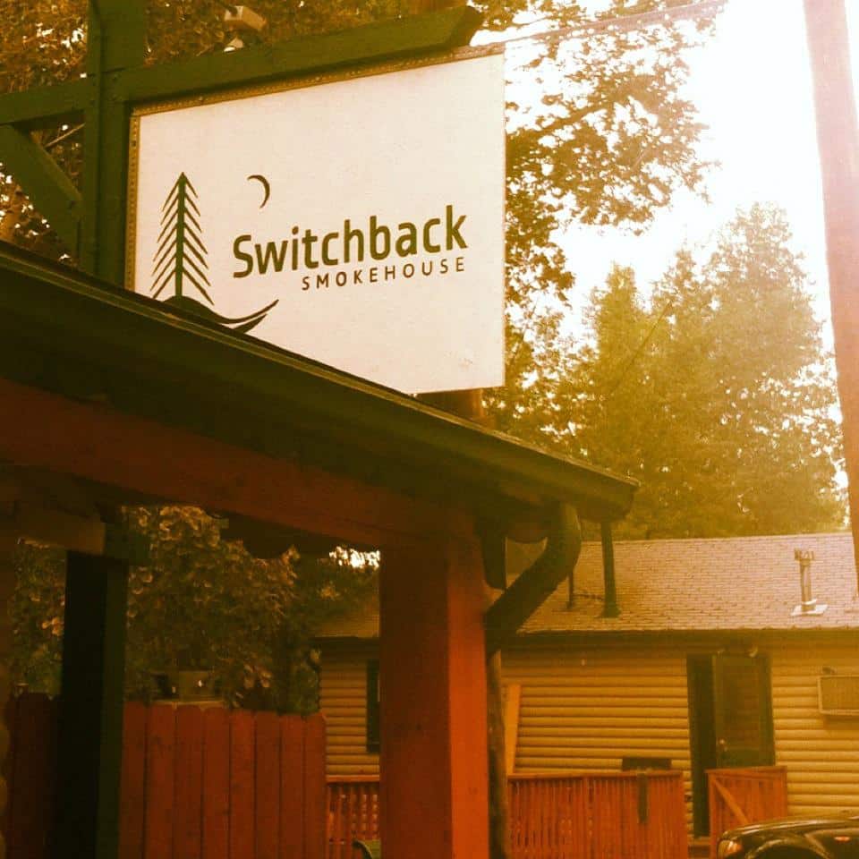 Hazy sun over outdoor sign for Switchback Smokehouse restaurant