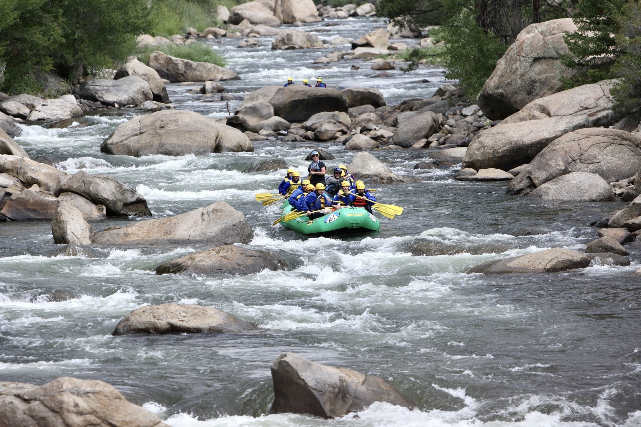 Rocky stream with two bright green rafting boats