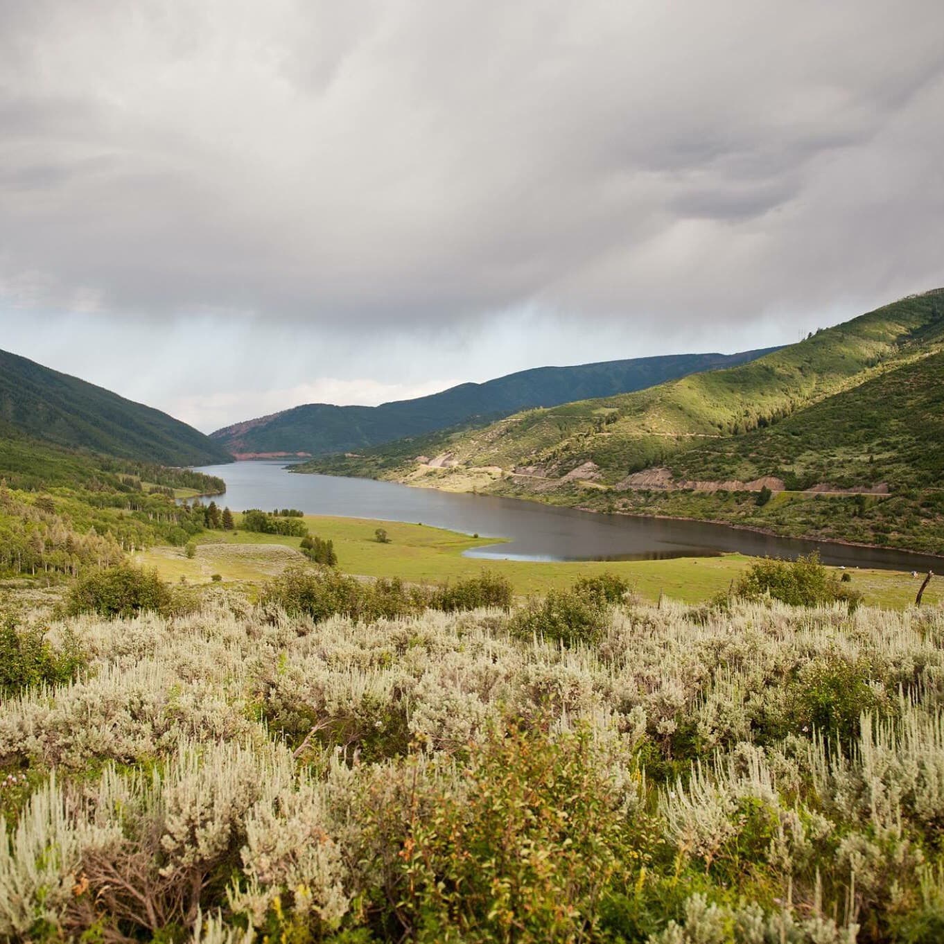 Lake surrounded by mountains and green rolling hills