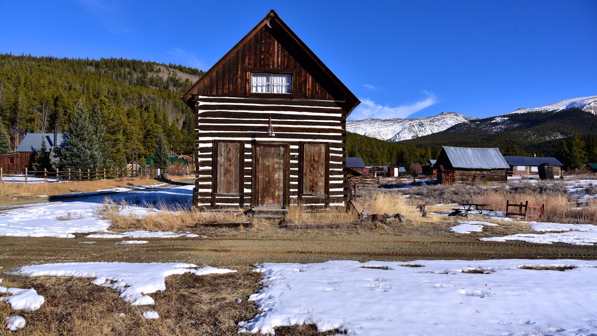 Historic wooden building in a semi-ghost town with some light snow on the ground