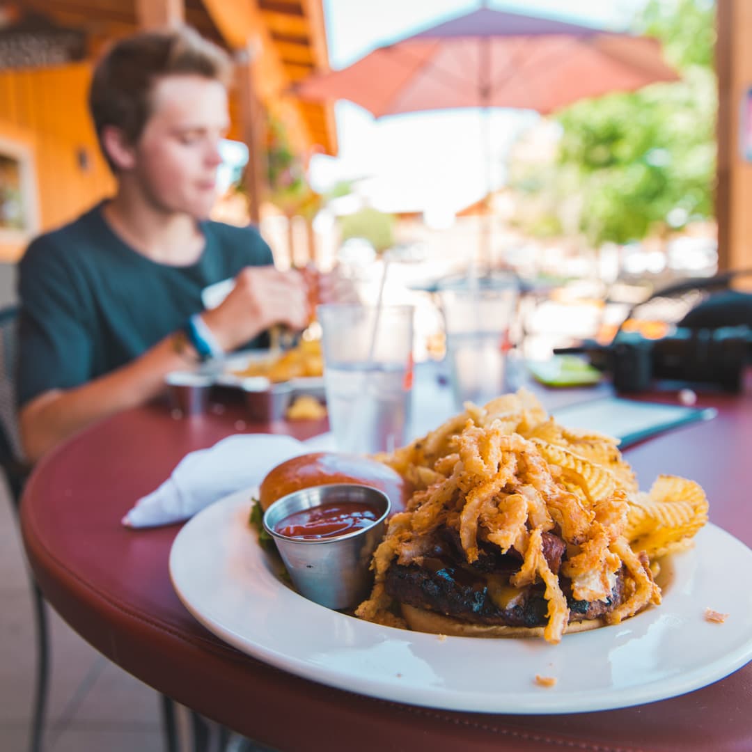 Cheesburger stacked high with fried onion strings with potato chips at 8 Mile Bar & Grill Canon City CO