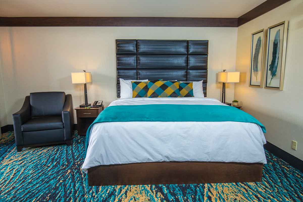 Hotel room with teal carpet and a leather armchair