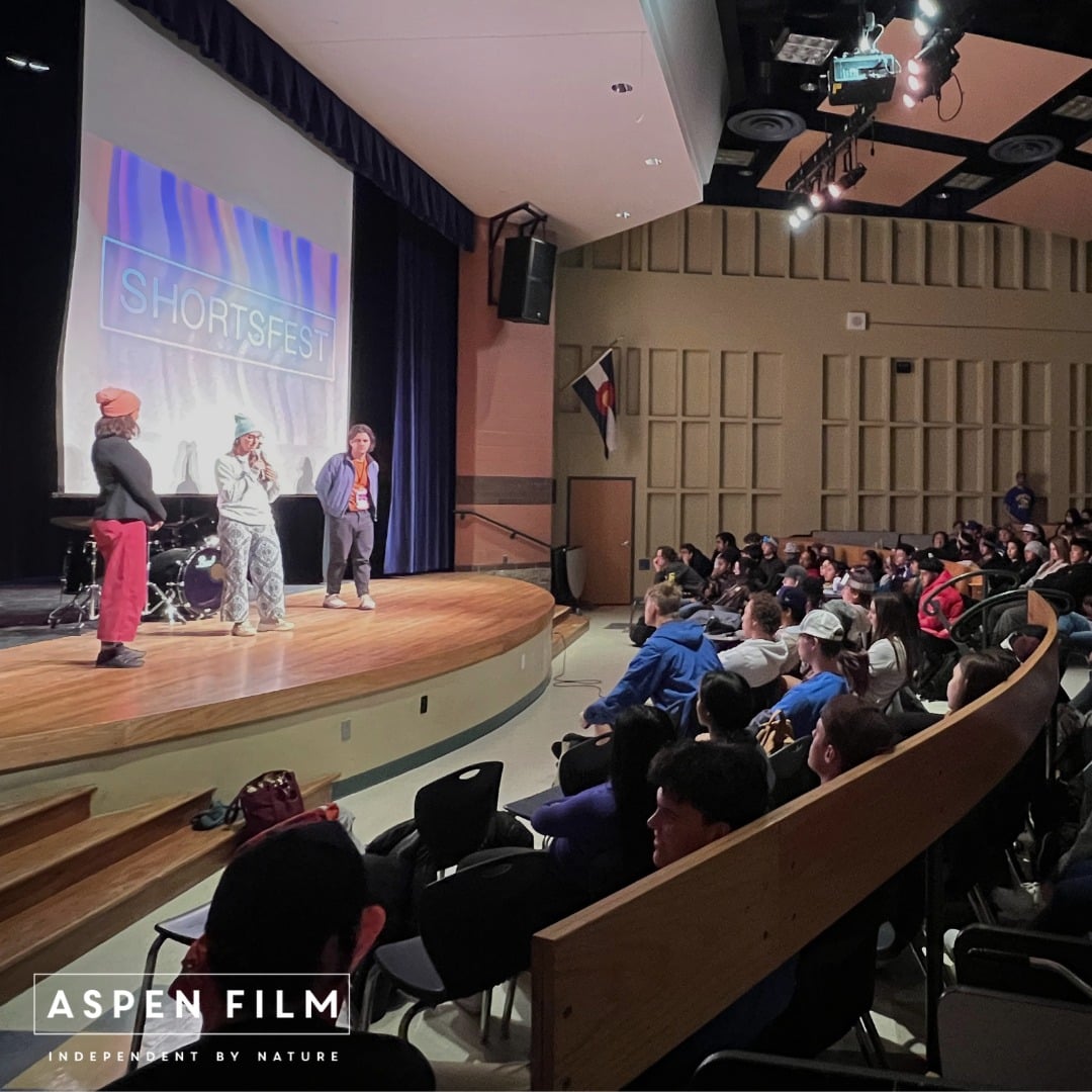 Three people standing on a stage in front of an audience at a film festival