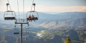 Two people riding up a ski lift in the summertime