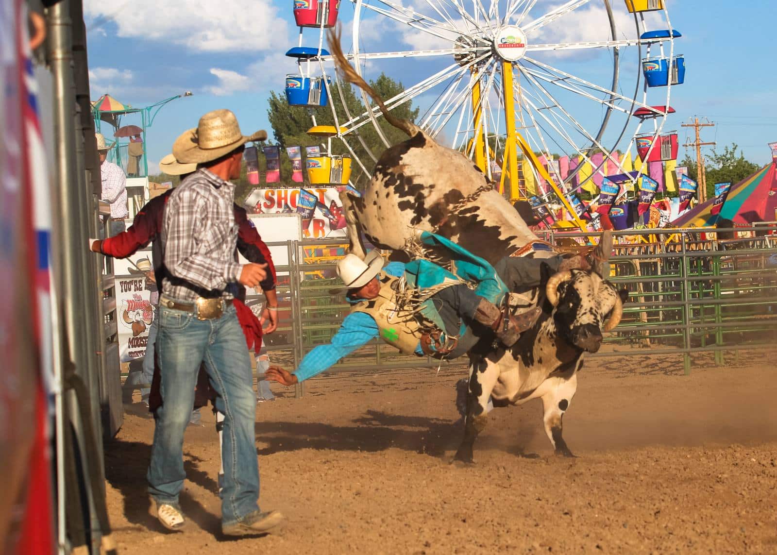 Rider falling off a bull in an arena at the county fair