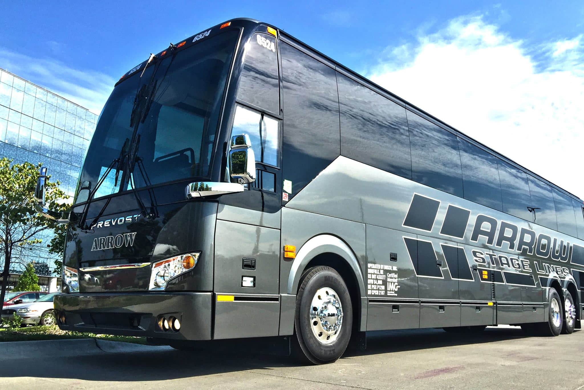 Large black Arrow Stage Lines charter bus parked in front of glass building in Denver