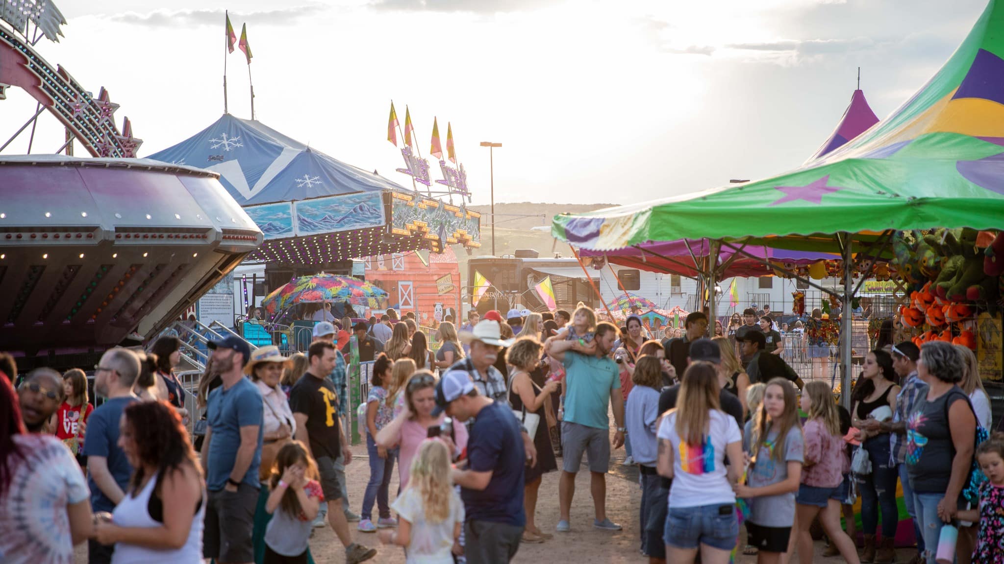 Crowds of people inbetween carnival rides at a county fair