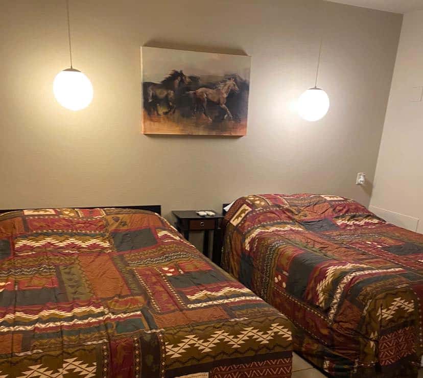 Hotel room with two double beds with aztec patterned comforters and a mounted painting of a horse running at the Fowler Inn.