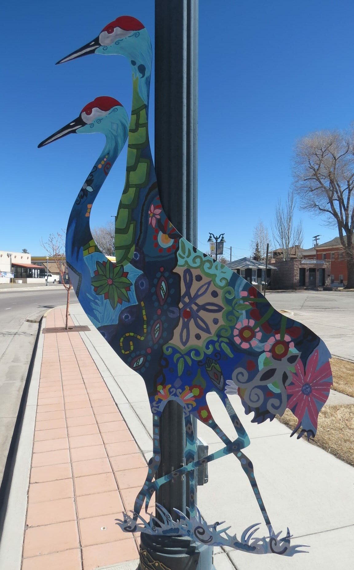 Painted crane shape hung up on town lamp pole