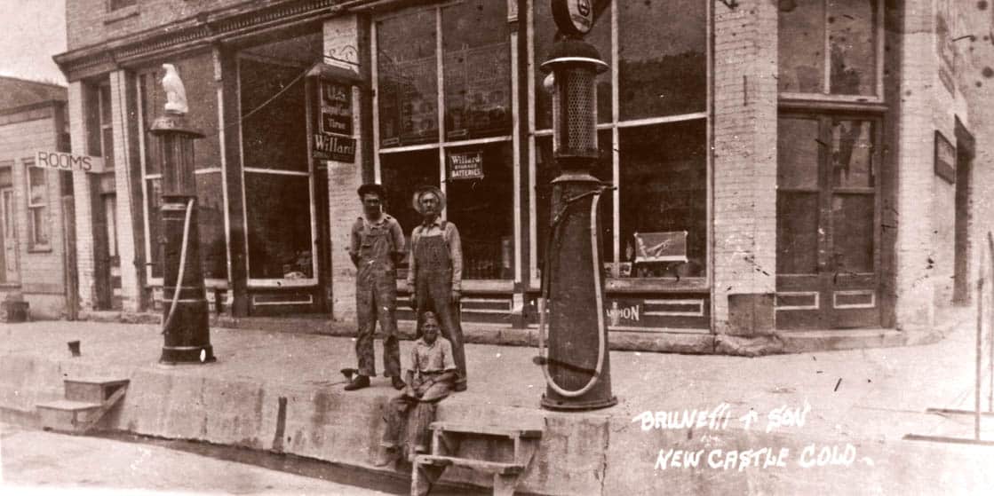 Historic photo of three people sitting on the curb in front of the Ore House Inn building