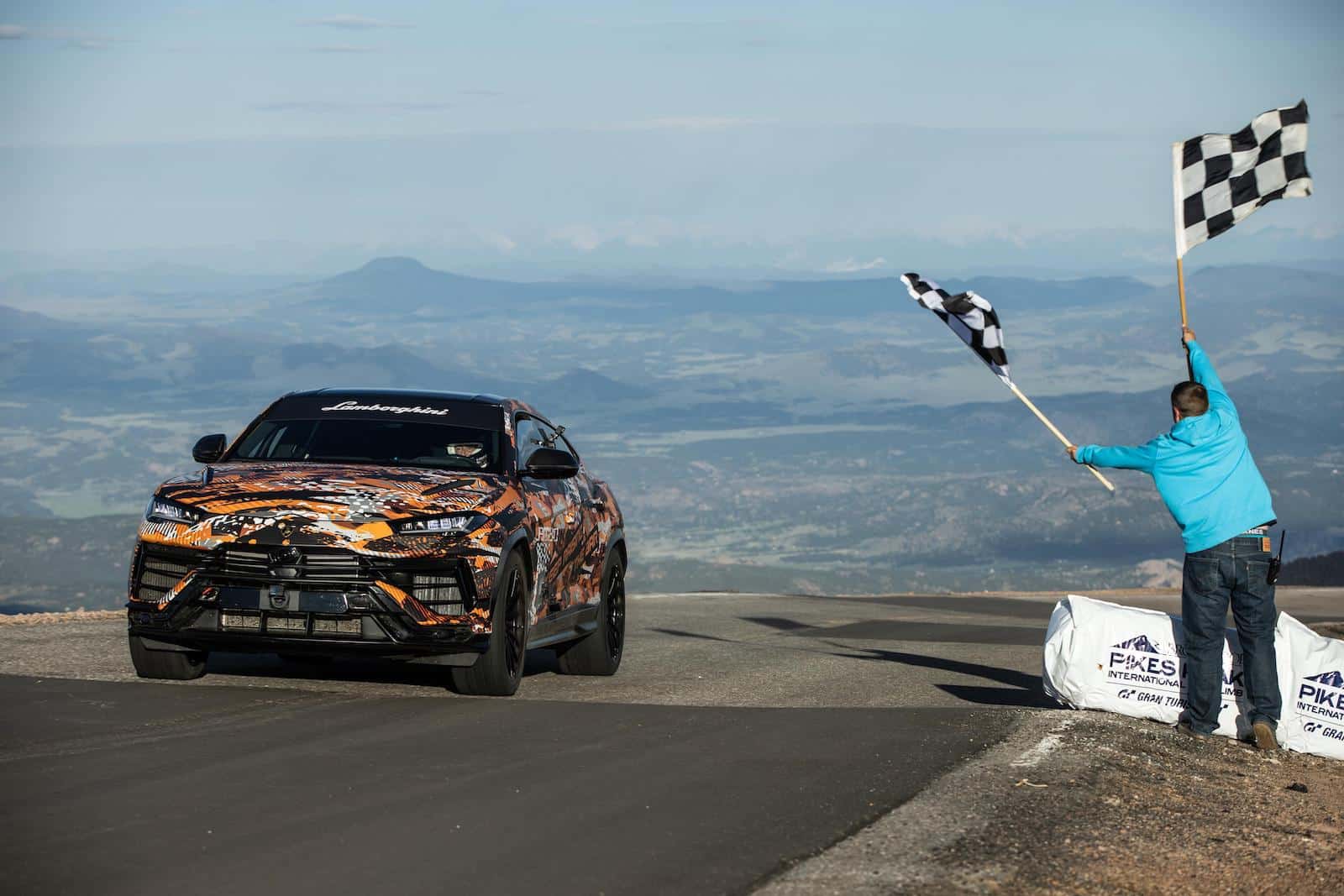 Lamborghini Urus Takes Pikes Peak's SUV Record on Pikes Peak International Hill Climb with guy waiving checkers flags