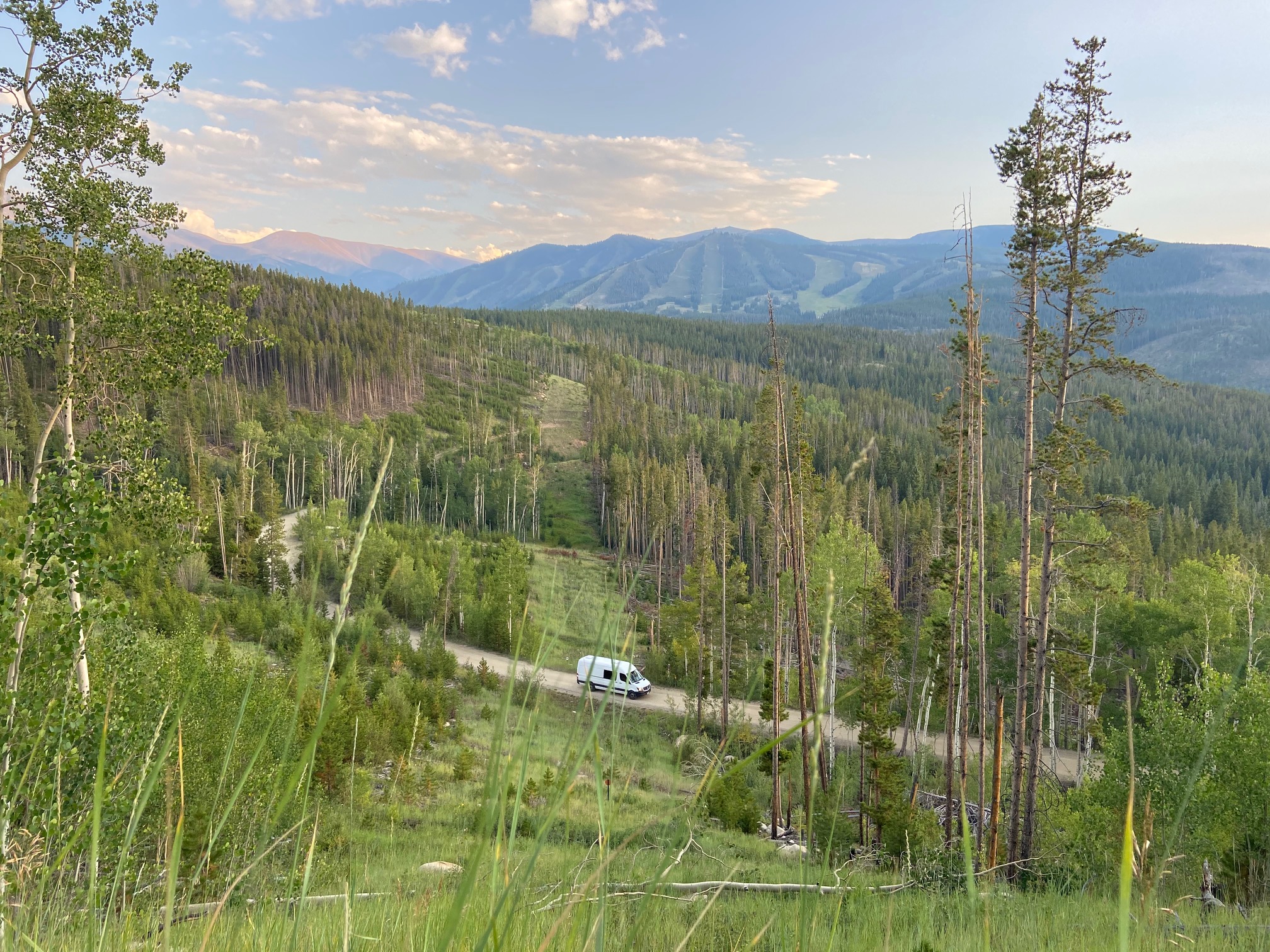 Overlooking a white camper van driving up Rollins Pass in summertime Winter Park Colorado