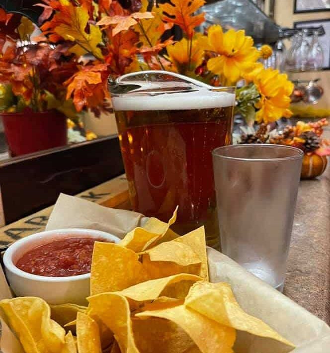 Pitcher of beer, glass of water, and platter of chips and salsa on the table at the Tamarack Grill in Fowler.