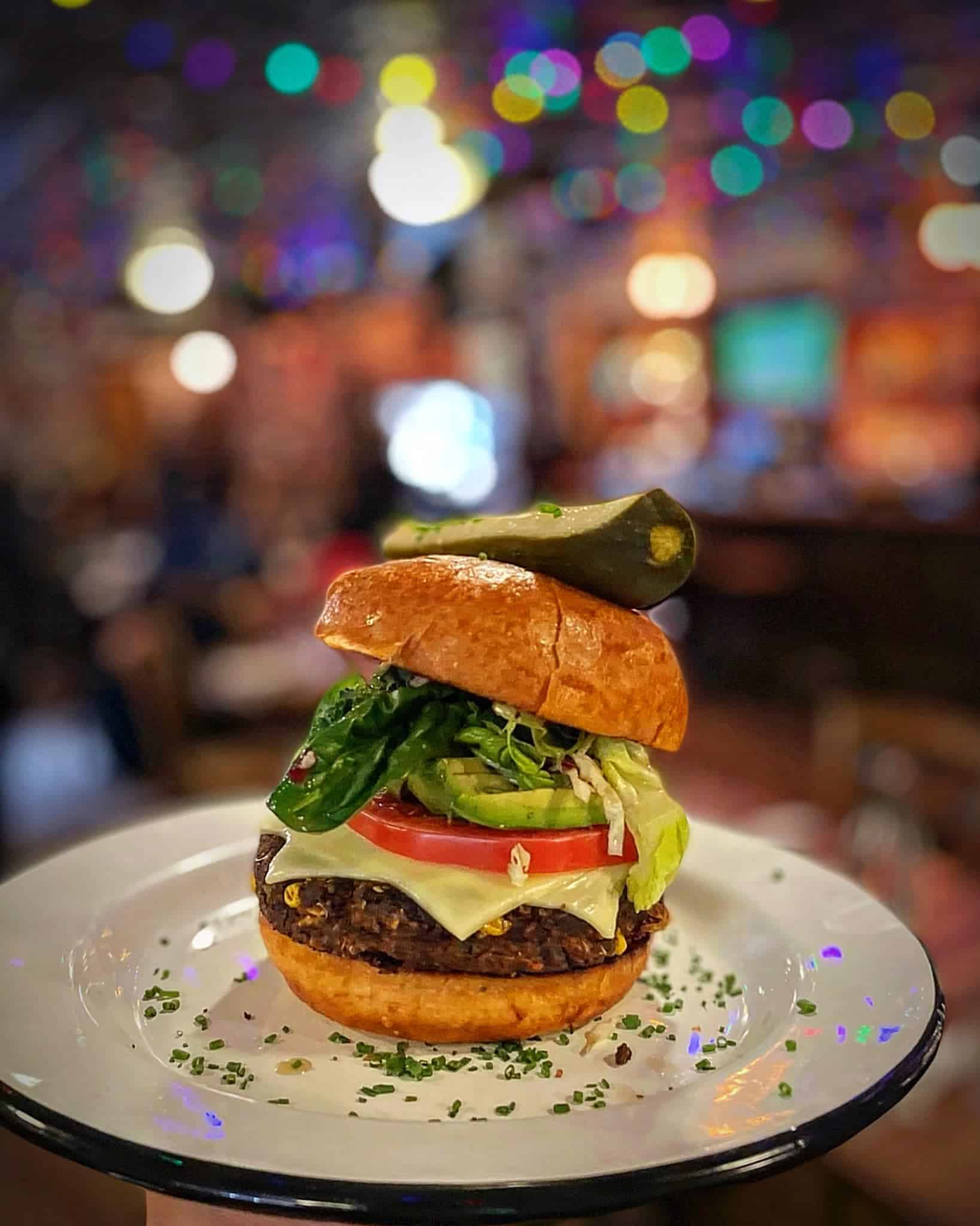 Veggie burger with a pickle on top on a plate at Woody Creek Tavern