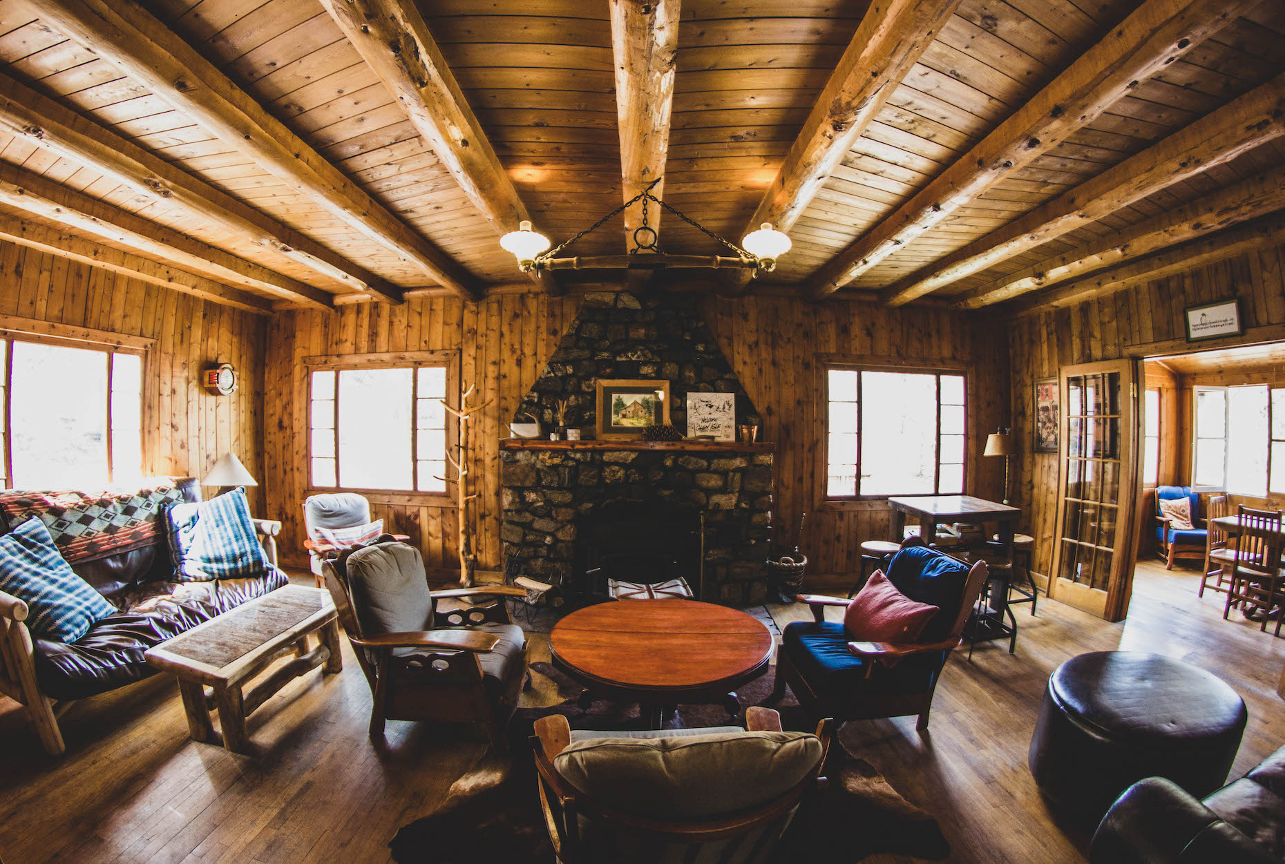 Interior of a log cabin at Glen Isle Resort with fireplace in the middle and sitting chairs around it