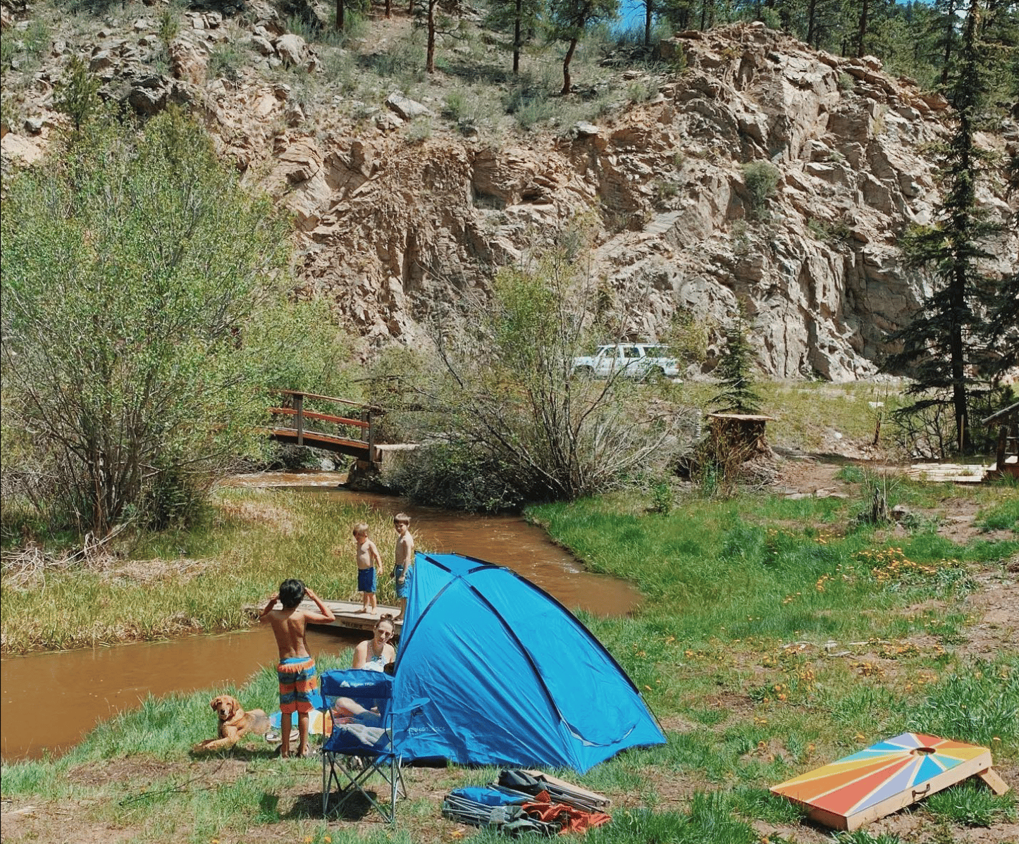 Blue tent pitched in the grass on the banks of a small creek at Glen Isle Resort. 