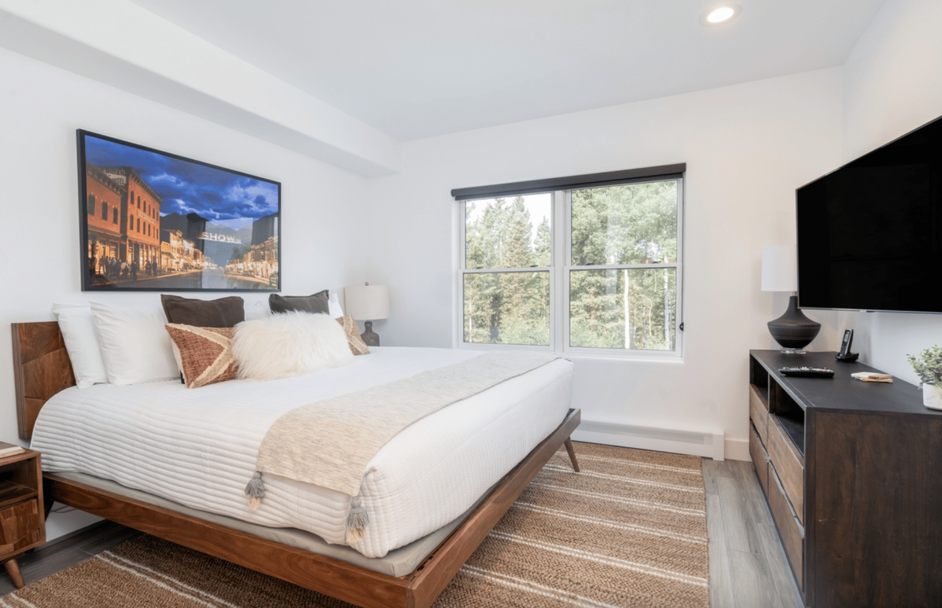 Accommodation room at the Bear Creek Lodge. One king bed with beige bedding, an armoire with a small TV, and a window overlooking a snowy landscape