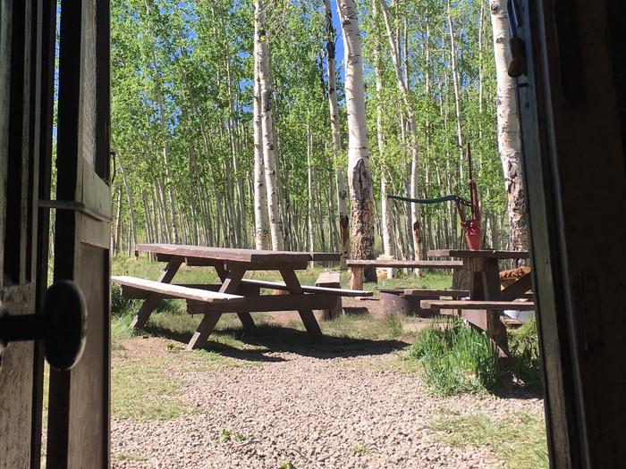 A wooden picnic table and fire ring seen outside the Bassam Guard Station cabin