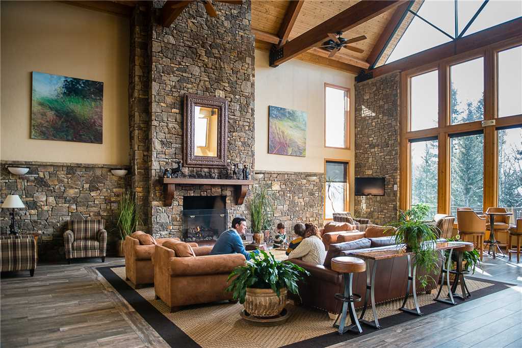 Lobby at Bear Creek Lodge with a huge stone fireplace, several plush sitting chairs, and vaulted ceilings with floor-to-ceiling windows letting in natural light.