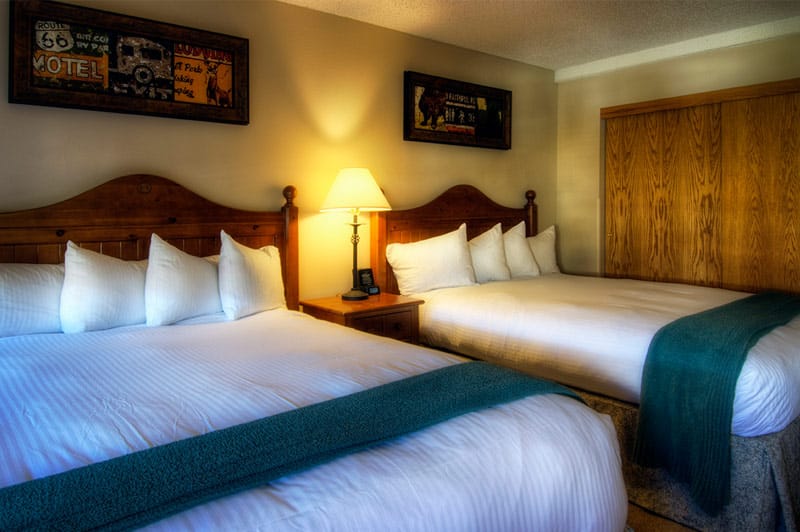 Double bed room at Beaver Run Resort. Two queen beds with white sheets and pillows and teal accent blankets. 