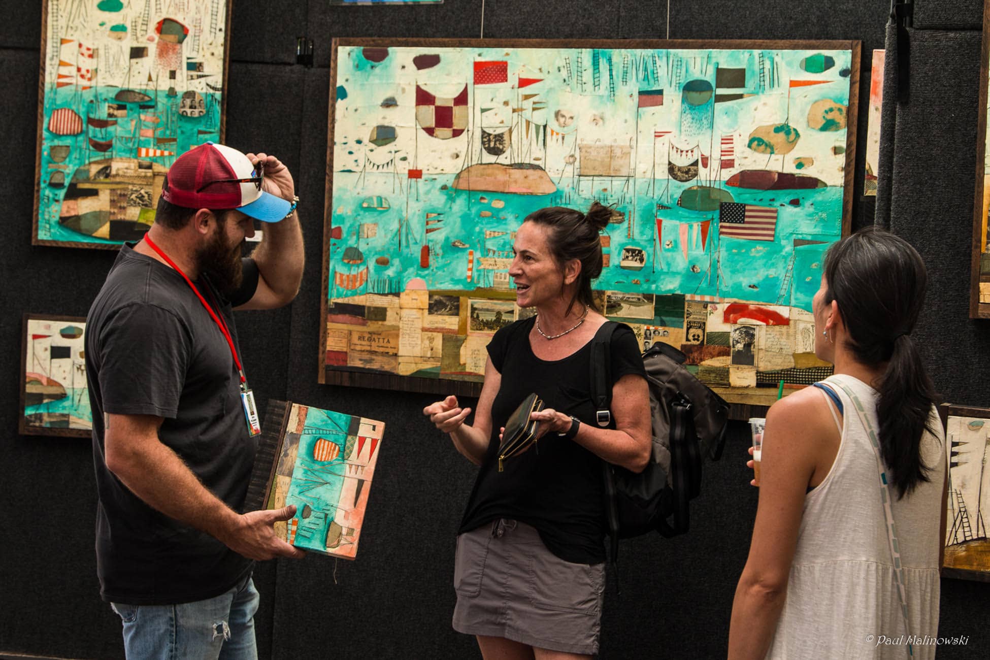 Three people standing around a painting at the Cherry Creek Arts Festival 