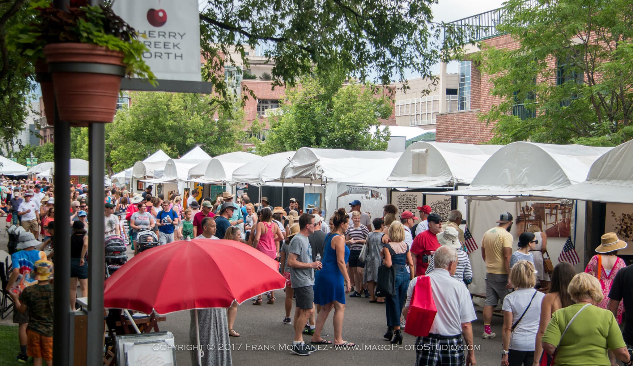 Large crowds of people wandering along closed off street full of vendors at the Cherry Creek Arts Festival in Denver