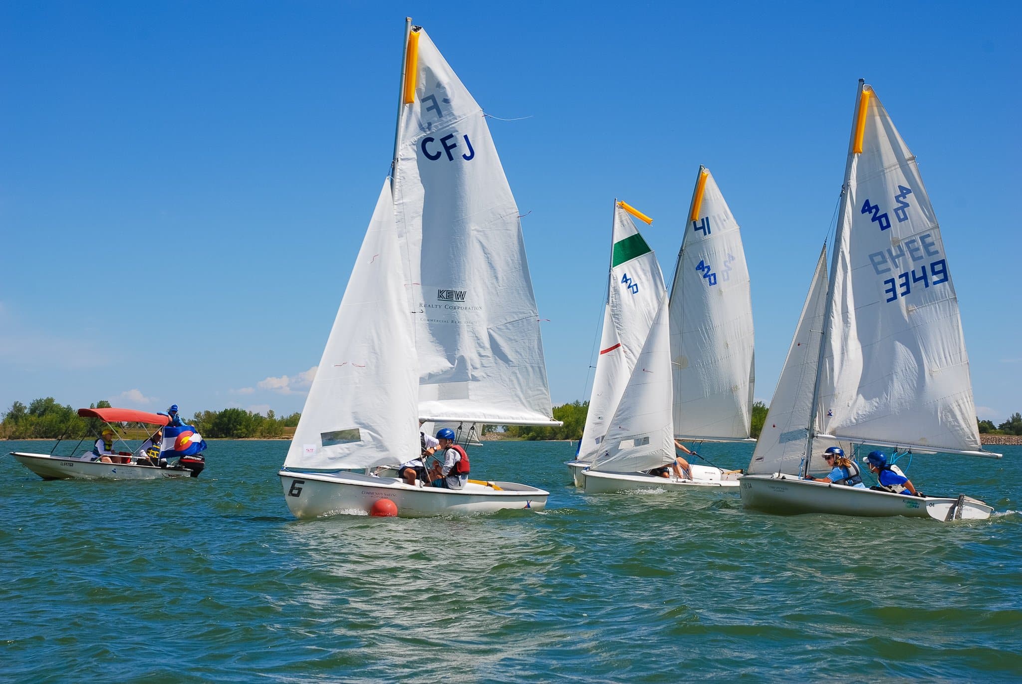 4 small white sailboats on Cherry Creek State Park reservoir on a bluebird sky day