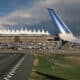 Image of an airplane wing with the Denver International Airport in the background